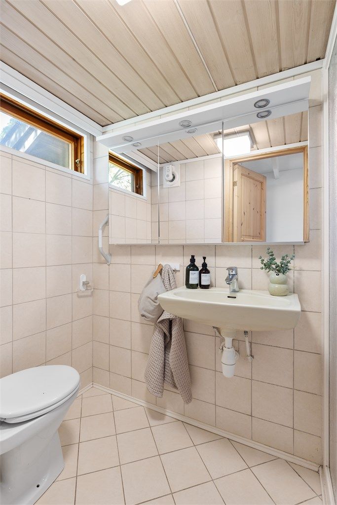 Badet er utstyrt med vegghengt servant, speilskap med belysning og toalett.
