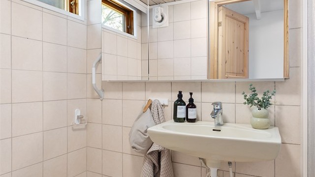Badet er utstyrt med vegghengt servant, speilskap med belysning og toalett.