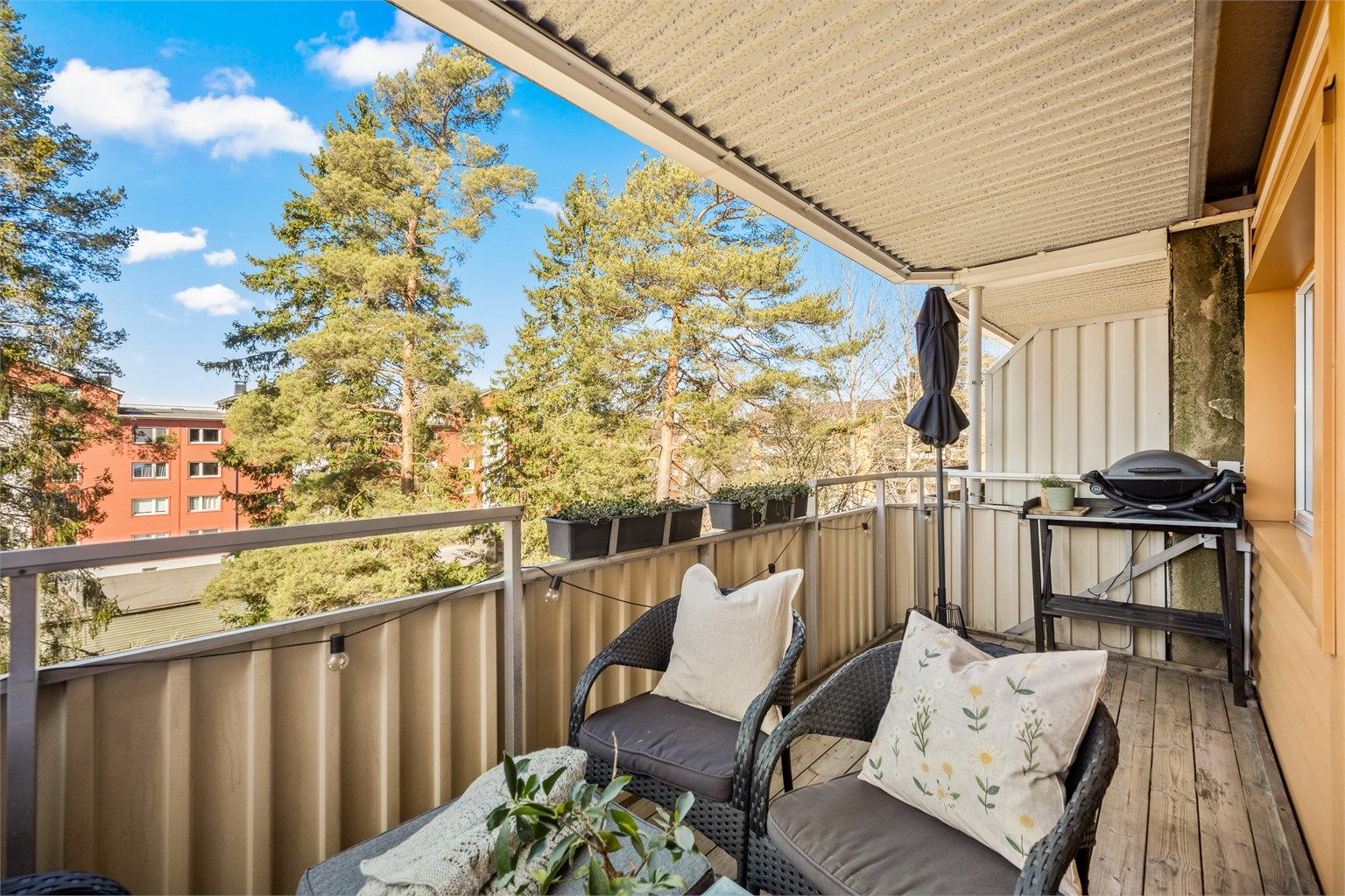 Balkongen er belagt med terrassebord og har et solid rekkverk i metall og fasadeplater.