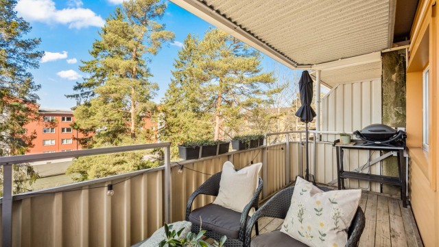 Balkongen er belagt med terrassebord og har et solid rekkverk i metall og fasadeplater.