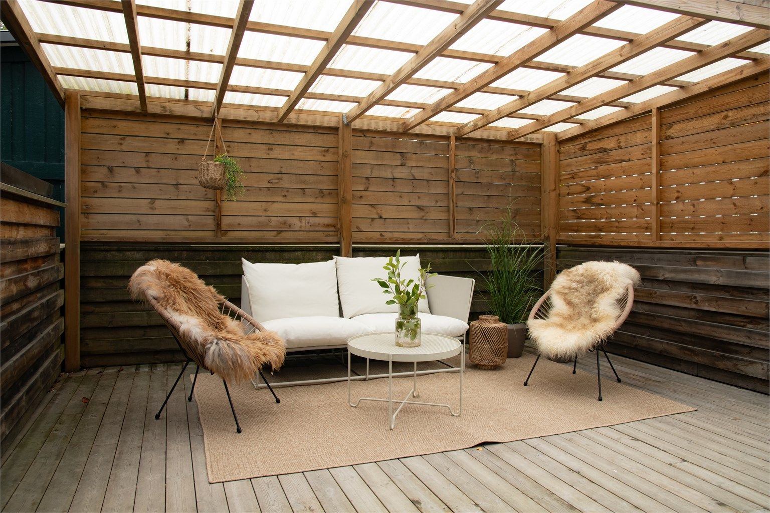 Overbygget uteplass med levegger og god plass til en lun sittegruppe.