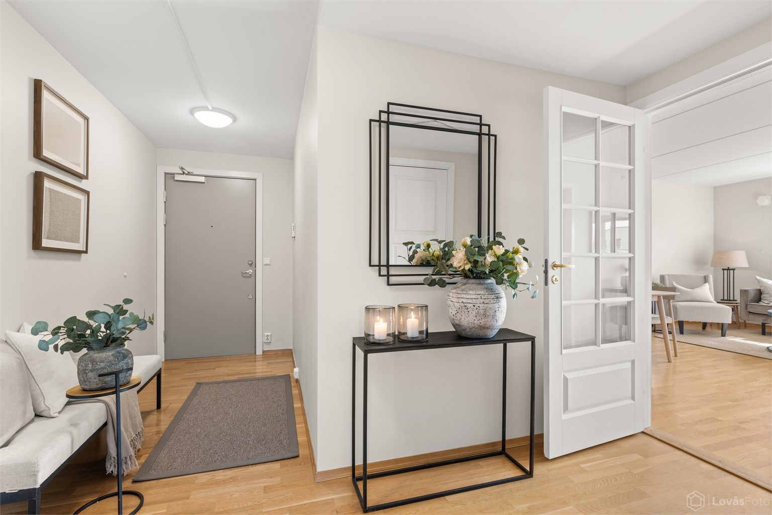Innbydende entré med profilert glassdør som leder inn til stuen. Parkett på gulv.