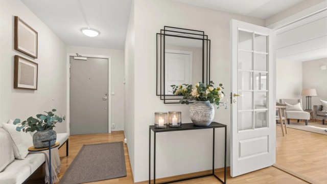 Innbydende entré med profilert glassdør som leder inn til stuen. Parkett på gulv.