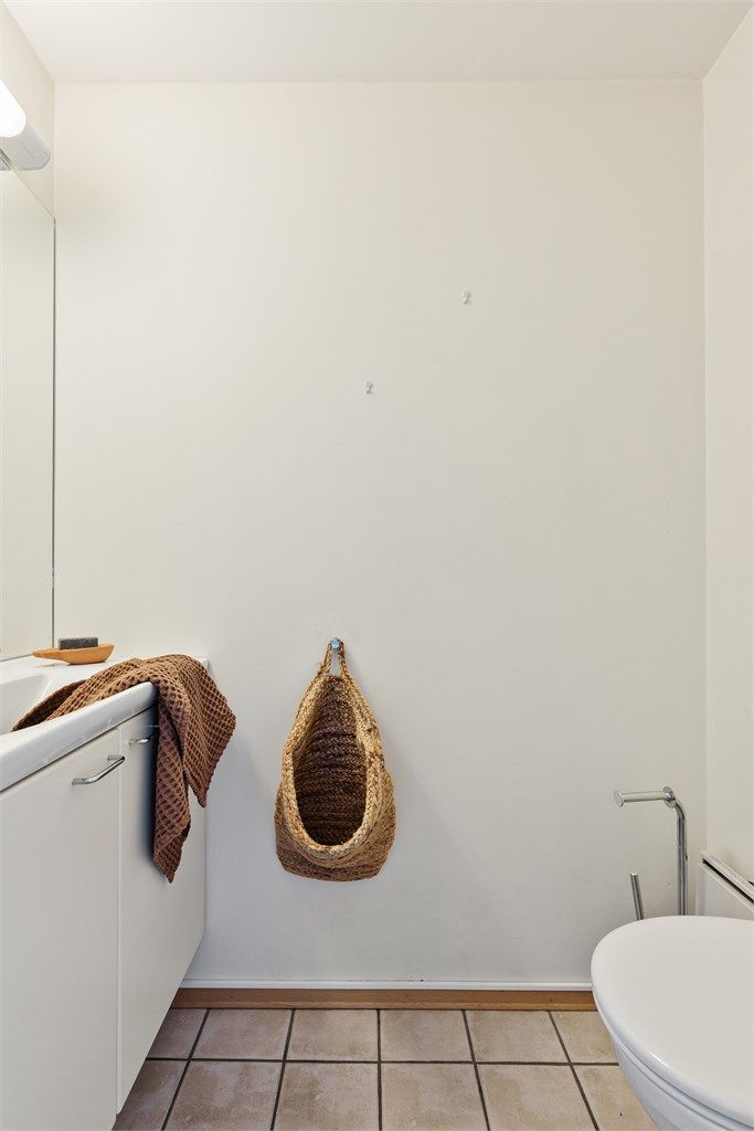 Toalettrom med gulvflate belagt med fliser. Malte veggflater. Malte flater i himling. Vegghengt servantinnredning. Vegghengt toalett. Mekanisk avtrekk med ventil i himling.