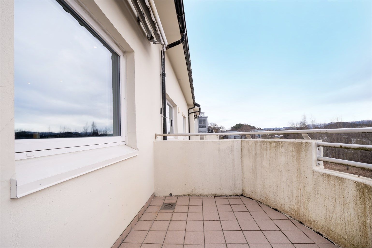 Balkongen har flislagt gulv og plass til en sittegruppe.