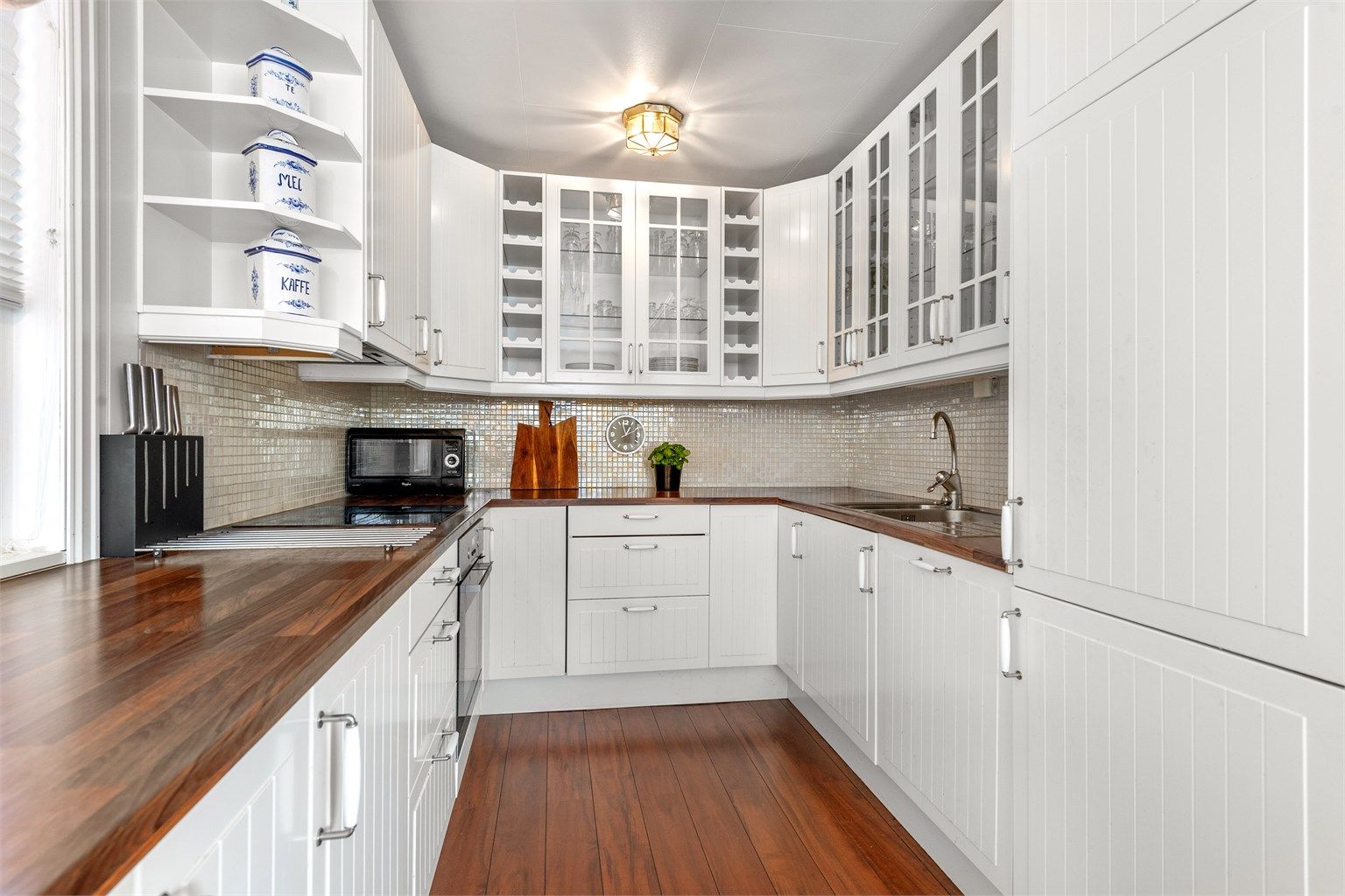 Kjøkkenet har mosaikkfliser mellom benk og overskap. Komfyr, oppvaskmaskin og kjøl-/fryseskap medfølger handelen.