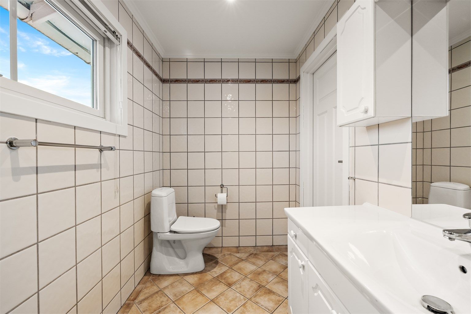 Badet er innredet med servantmøbel, toalett og badekar.