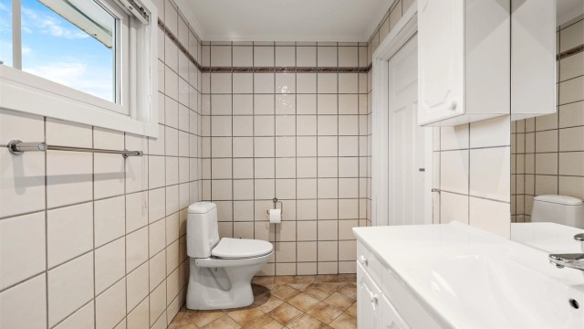 Badet er innredet med servantmøbel, toalett og badekar.