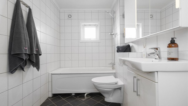 Baderommet fra 2012 har flislagte overflater, gulvvarme og badekar.
