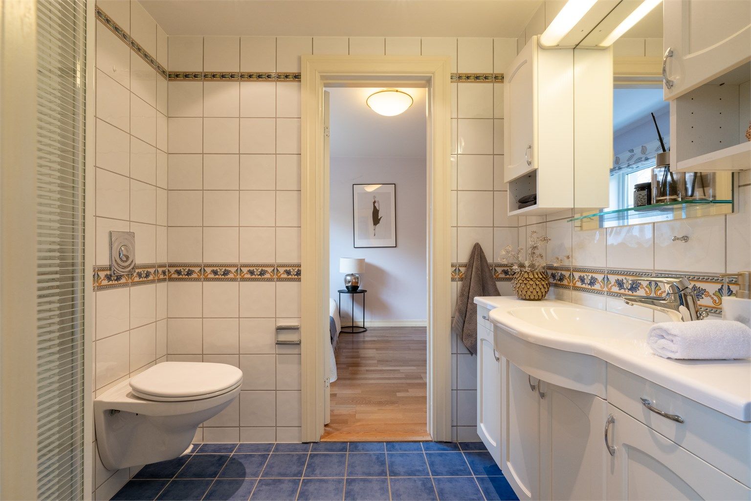 Baderom 2 er av god størrelse og ligger plassert mellom soverom 2 og 3. Det er innredet med vegghengt servantskap med ovenpåliggende vask, samt speil, skap og lys over servanten.