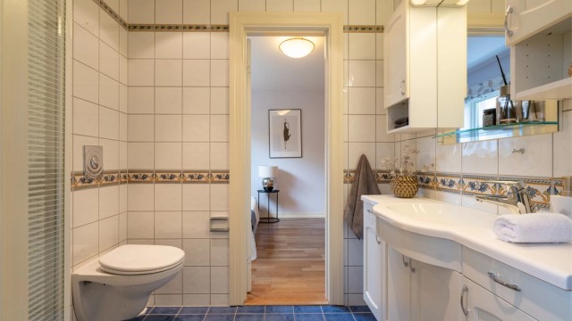 Baderom 2 er av god størrelse og ligger plassert mellom soverom 2 og 3. Det er innredet med vegghengt servantskap med ovenpåliggende vask, samt speil, skap og lys over servanten.