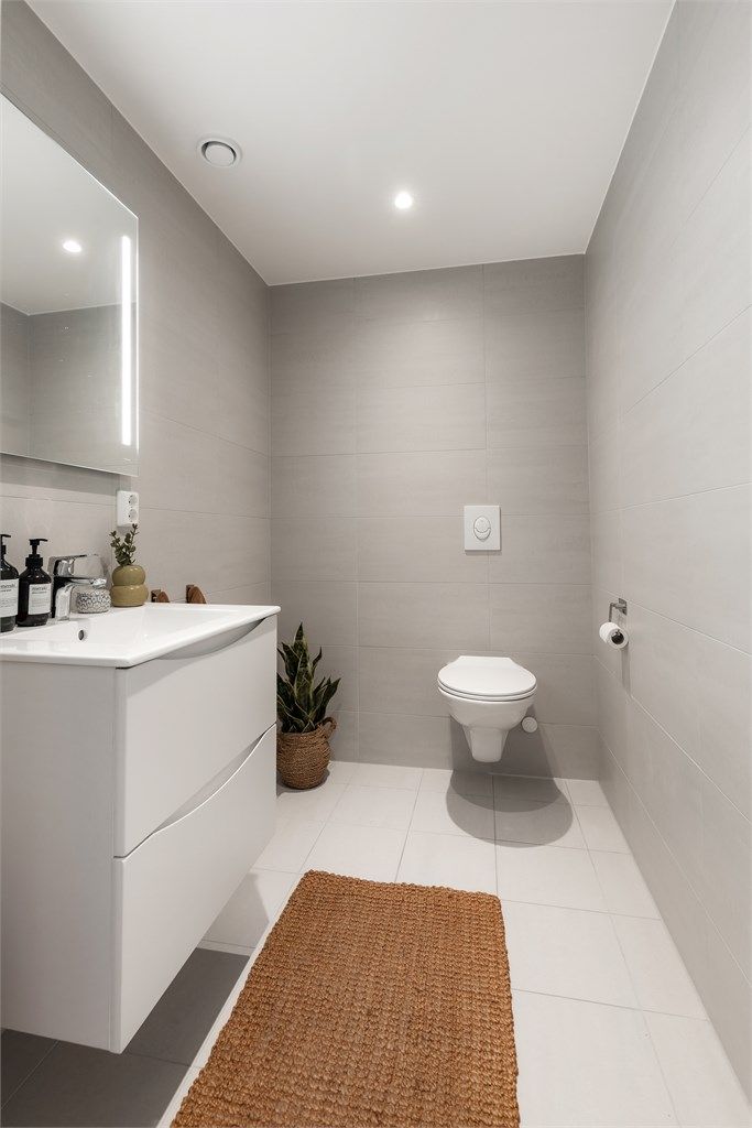 Toalettrom fra byggeår. Flislagt gulv med gulvvarme og flislagte vegger. Malt himlingsflate med downlights. Servant med ett-greps armatur og speil. Innebygd sisterne med vegghengt toalett. Avtrekksventil i himling.