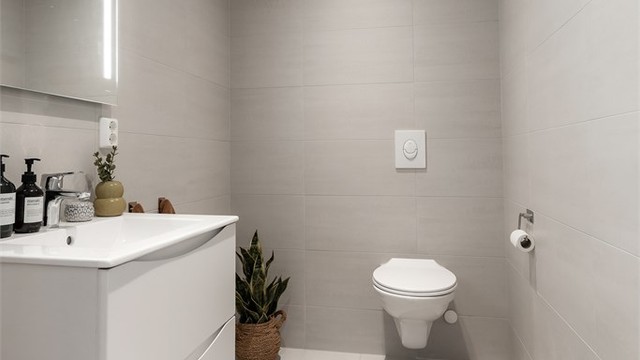 Toalettrom fra byggeår. Flislagt gulv med gulvvarme og flislagte vegger. Malt himlingsflate med downlights. Servant med ett-greps armatur og speil. Innebygd sisterne med vegghengt toalett. Avtrekksventil i himling.