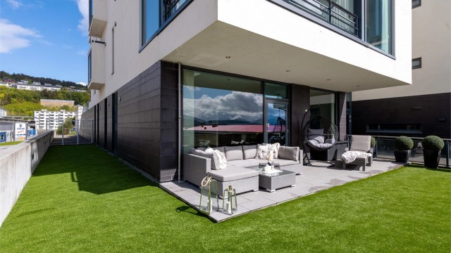 Solrikt uteareal på 91 m2 med fliser og kunstgress