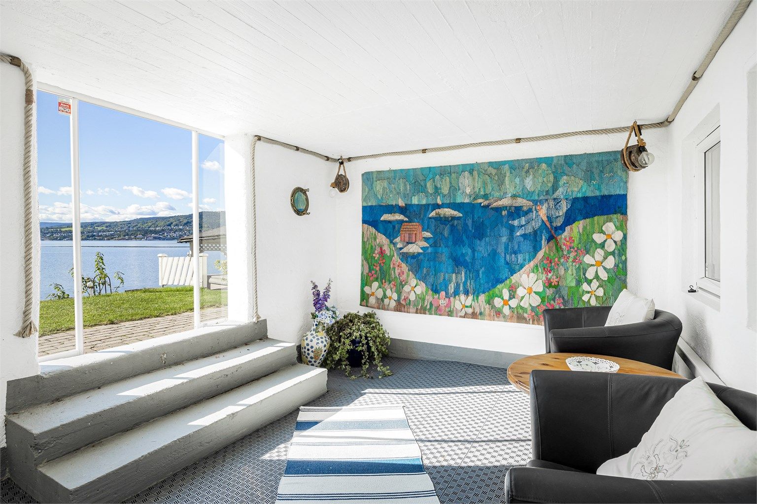 Innglasset terrasse i underetasjen med skyvedør i glass mot uteområdet.