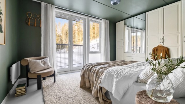 Hovedsoverommet vender ut mot marka med stort vindu og dobbel balkongdør til en fransk balkong