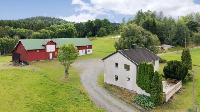 Eiendommen sett fra siden, med terrassen vendt mot jordene.