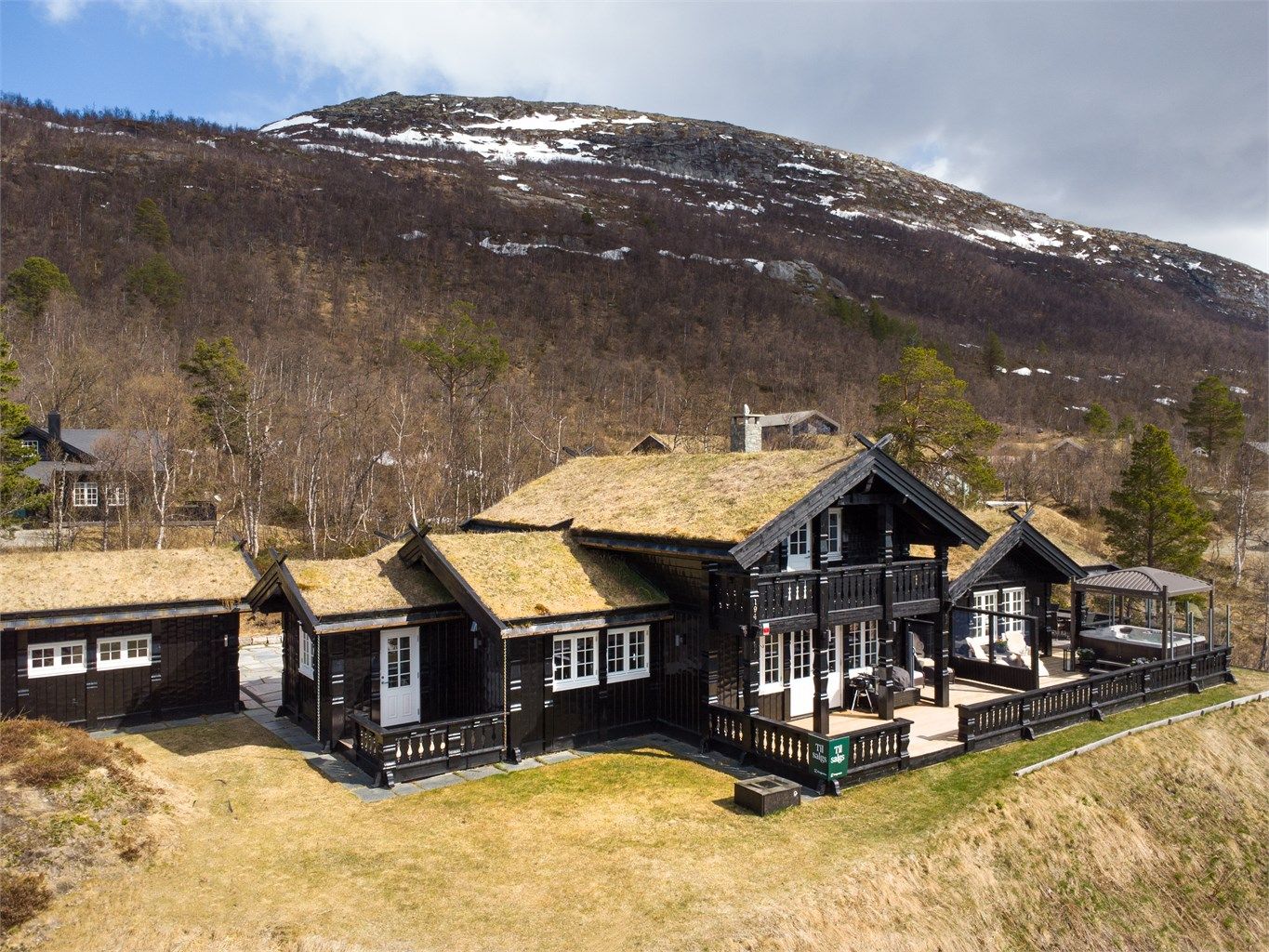 Hytta ligger høyt og fritt i terrenget med utsikt over hyttefeltet og fjellene.