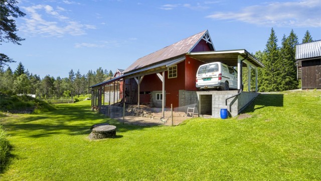 Eiendommen inkluderer en romslig låve med tilhørende hønsegård, carport og smøregrav.