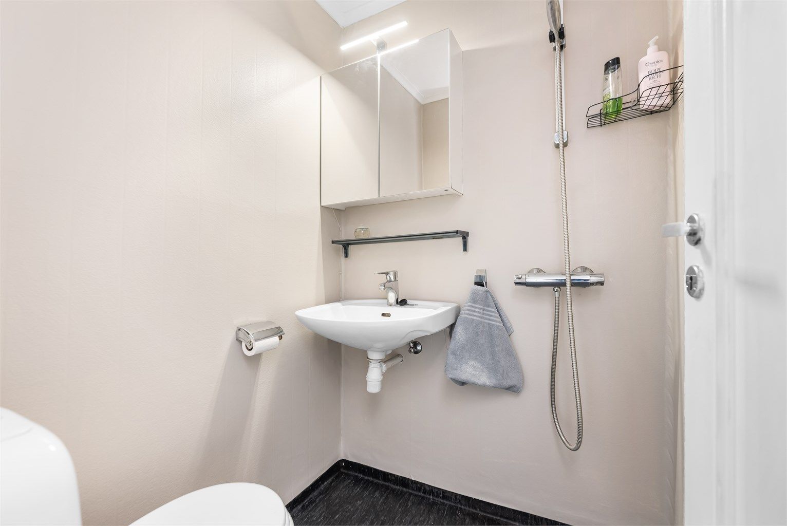 Baderom er fra ukjent eksakt årstall med gulvflate belagt med gulvbelegg. Badet er innredet med vegghengt servant med armatur, speilskap med overlys, dusjhjørne med forheng og gulvstående toalett.