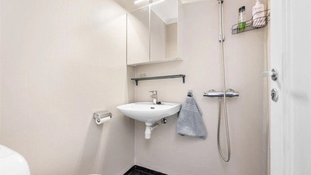 Baderom er fra ukjent eksakt årstall med gulvflate belagt med gulvbelegg. Badet er innredet med vegghengt servant med armatur, speilskap med overlys, dusjhjørne med forheng og gulvstående toalett.