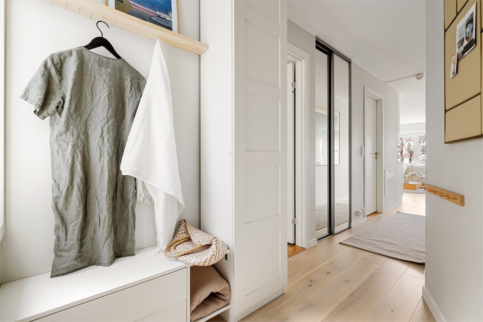 Romslig entré med lysmalte veggflater og lekker, enstavs eikeparkett på gulv