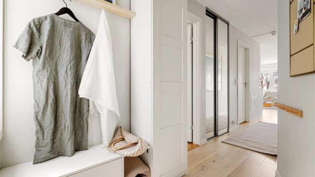 Romslig entré med lysmalte veggflater og lekker, enstavs eikeparkett på gulv