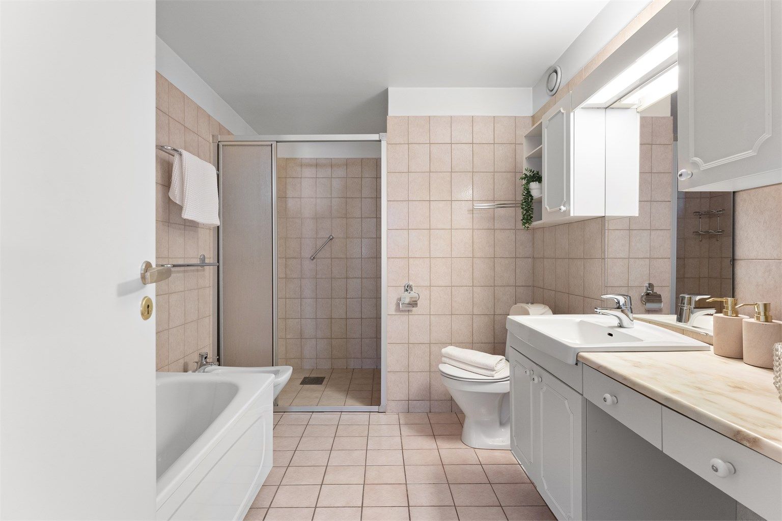Leiligheten har to bad. Dette badet i gangen er flislagt og har både dusjhjørne og bidé.