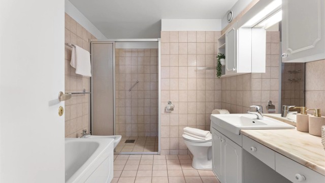 Leiligheten har to bad. Dette badet i gangen er flislagt og har både dusjhjørne og bidé.
