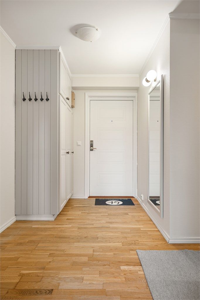 Innbydende entré med parkett på gulv og god plass til oppbevaring av yttertøy.