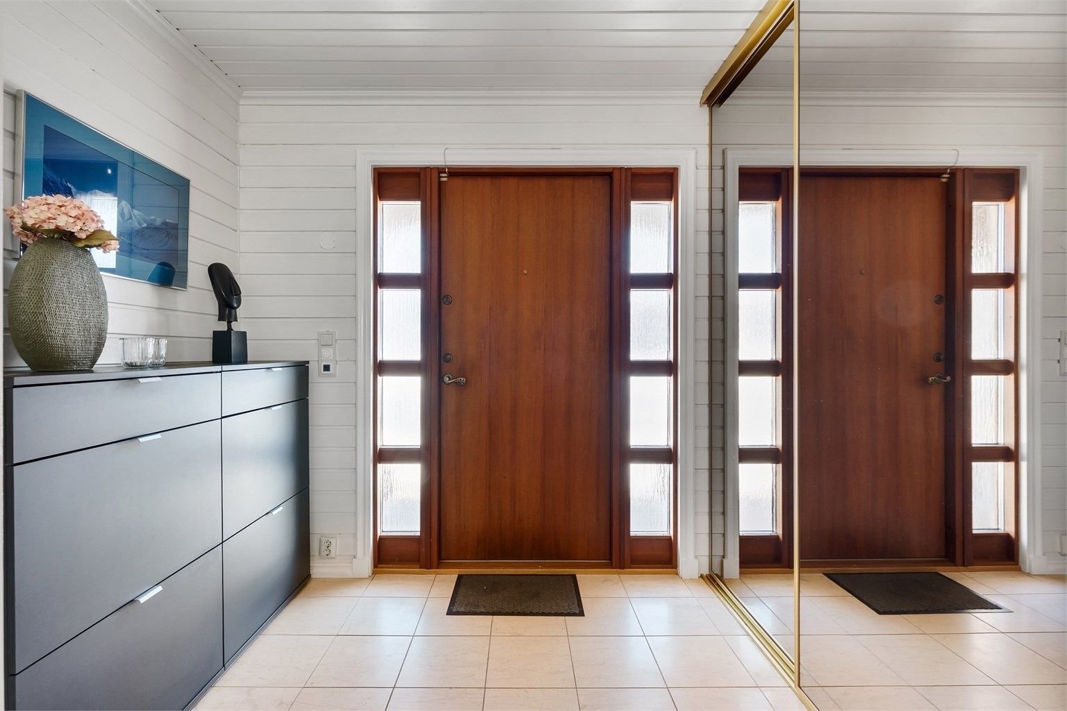 Entré med flislagt gulv, gulvvarme og skyvedørsgarderobe for praktisk oppbevaring.