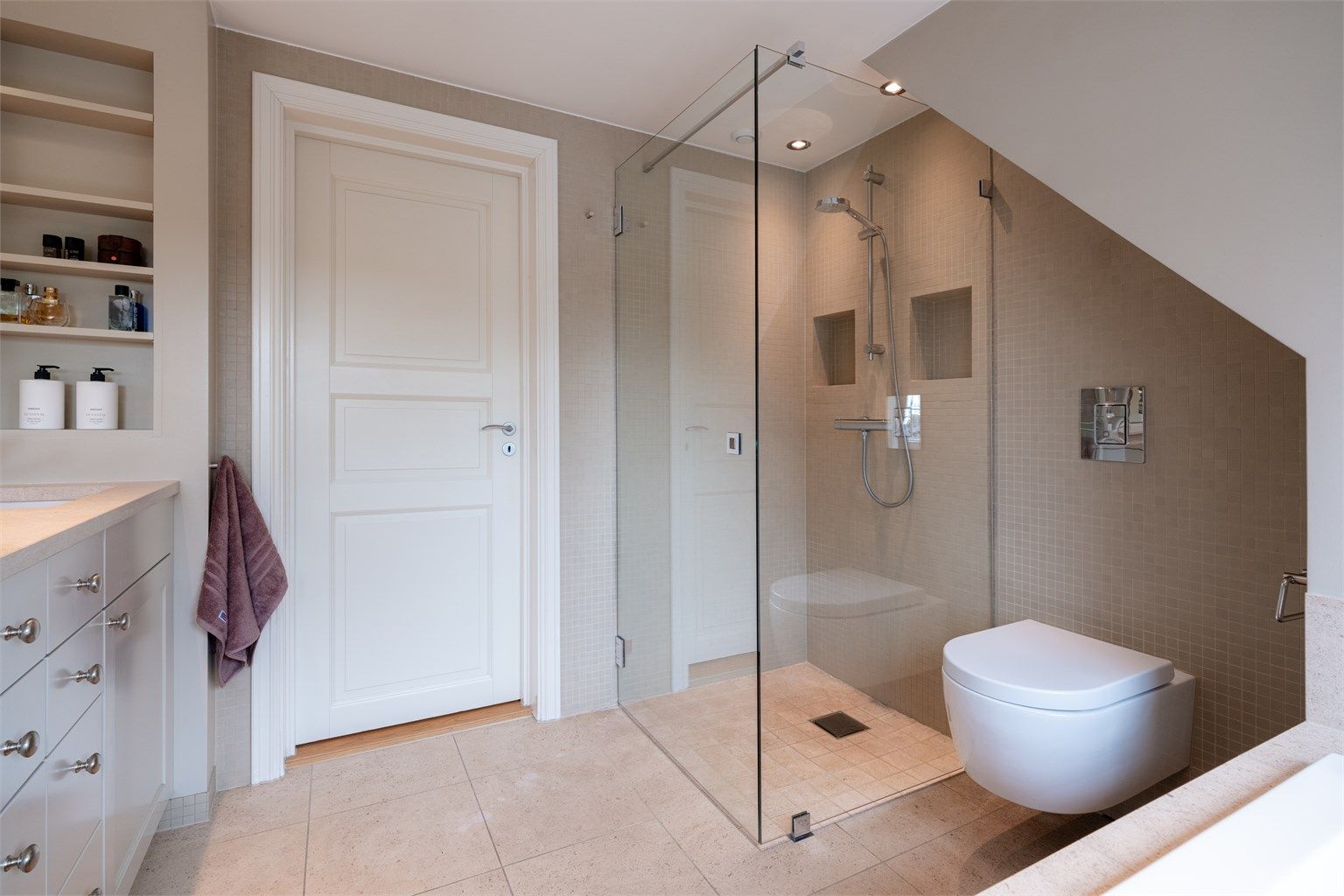 Den romslige dusjsonen med innfellbare glassdører gir badet et stilrent og åpent uttrykk.