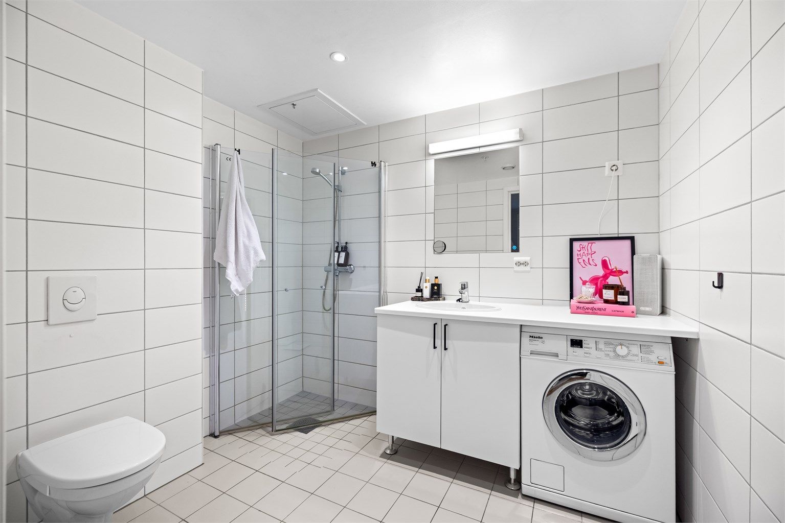 Bad fra 2018 med flislagte overflater og varmekabler i gulv, vegghengt toalett og opplegg for vaskemaskin.