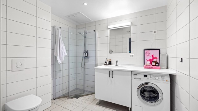 Bad fra 2018 med flislagte overflater og varmekabler i gulv, vegghengt toalett og opplegg for vaskemaskin.