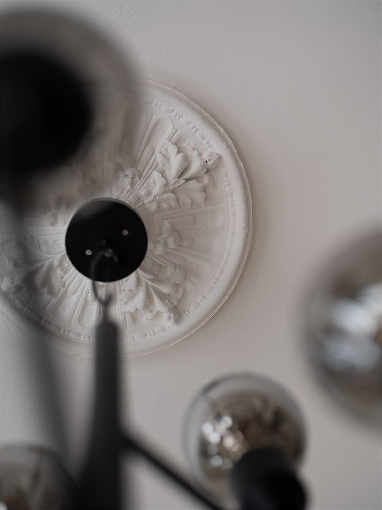 Nydelige, klassiske detaljer som rosett og stukkatur går igjen i leiligheten.