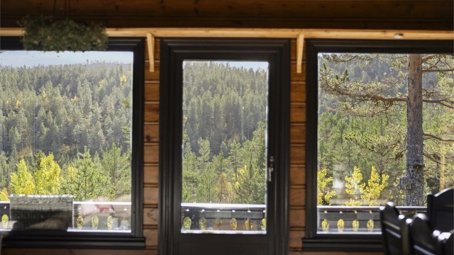 Utsyn over de skogkledde åsene gjennom vinduene og terrassedøren i stuen.