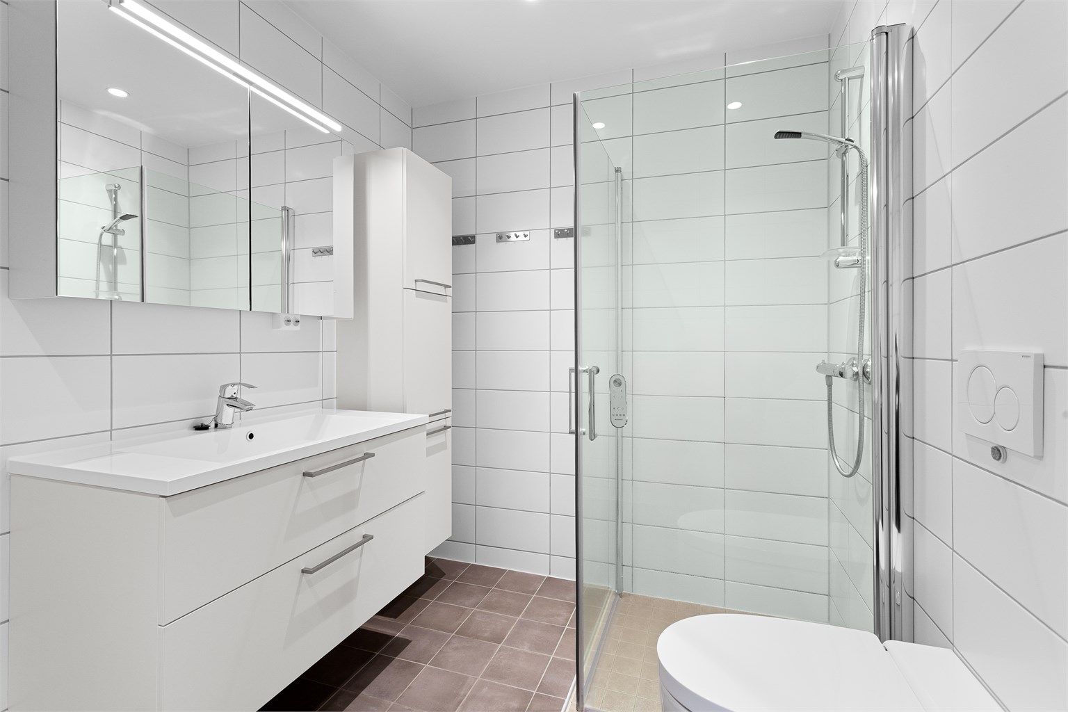 Flislagt bad med gulvvarme. Innredningen har heldekkende servant og godt med oppbevaring.