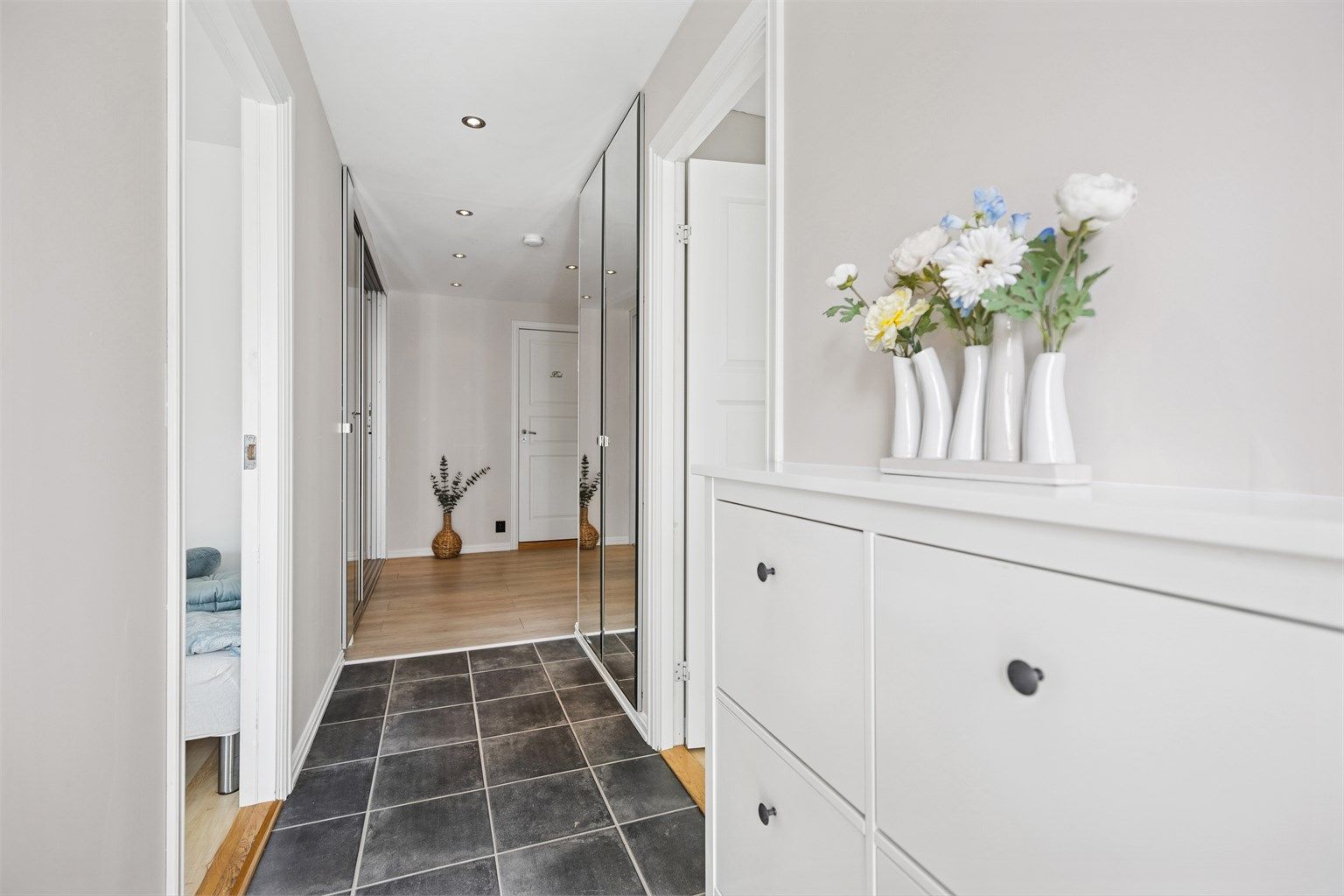 Lys og innbydende entré med gulvvarme og et stort garderobeskap med speildører. Lite speilskap med hurtiguttak til sentralstøvsuger.