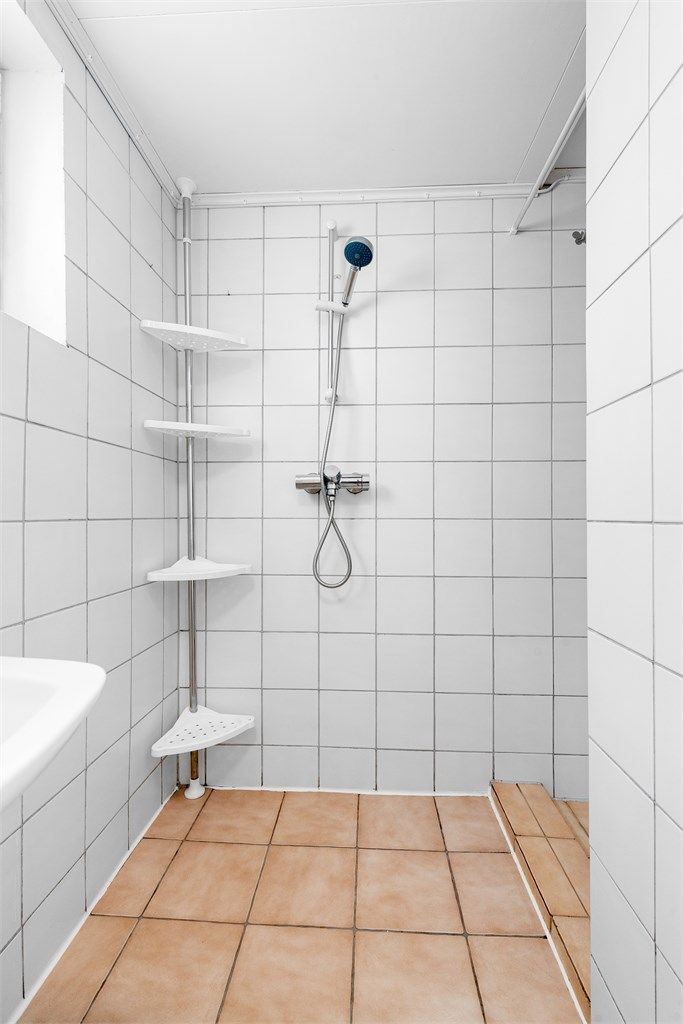 Dusjnisje med forheng og vegghengt dusjarmatur.