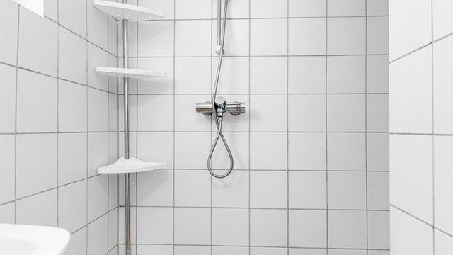 Dusjnisje med forheng og vegghengt dusjarmatur.