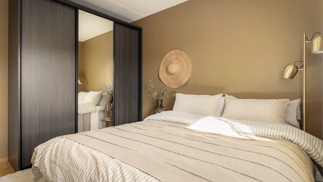 En romslig skyvedørsgarderobe med speilfronter gir rikelig med oppbevaringsplass på soverommet.