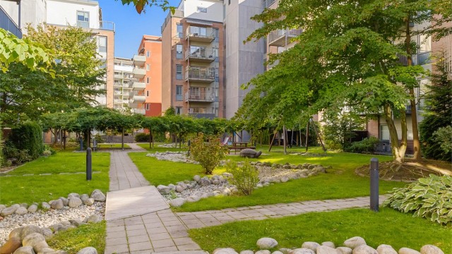 Frodige fellesarealer med beplantning, gangveier og hyggelige sitteplasser mellom byggene.