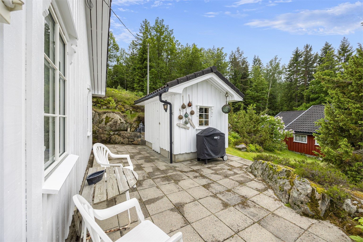 Uteplass med steinheller i tilknytning til den frittstående redskapsboden.