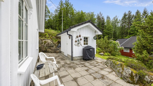 Uteplass med steinheller i tilknytning til den frittstående redskapsboden.