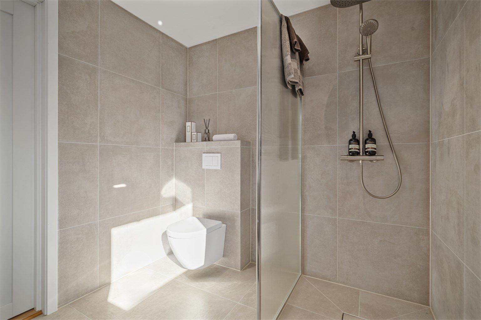 Regndusj, hånddusj, downlights og elektrisk styrt vifte kompletterer det moderne badet.