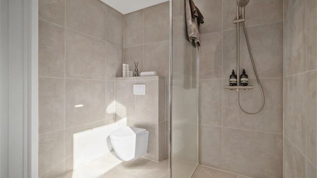Regndusj, hånddusj, downlights og elektrisk styrt vifte kompletterer det moderne badet.