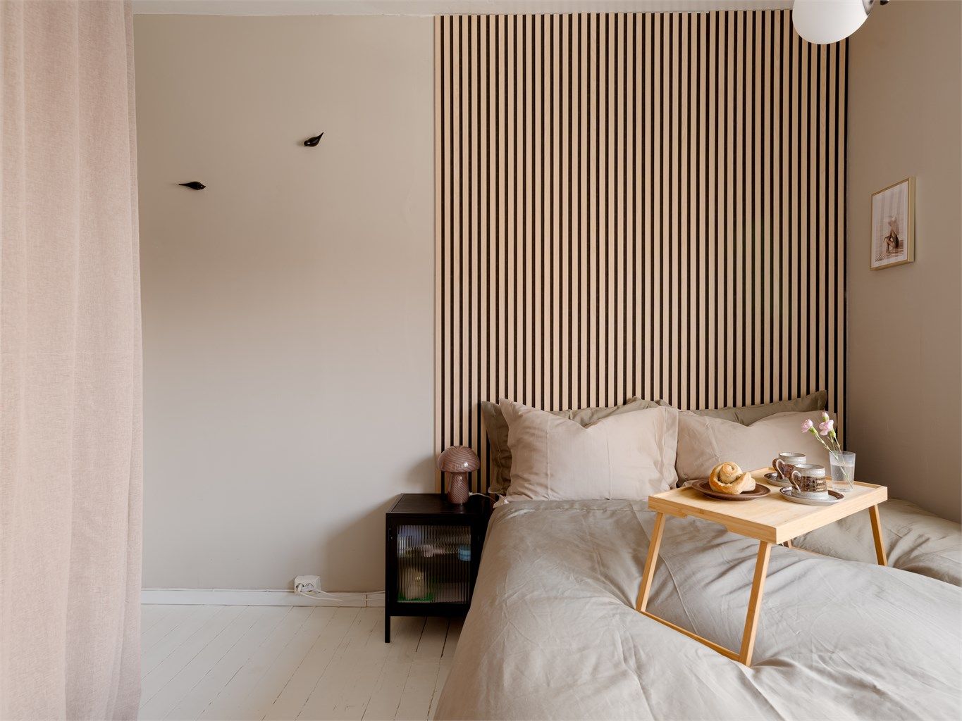 Rommet har malte tregulv og en gavlvegg med materialer som spiller på lag med miljøet rundt. Organisk og vakkert!