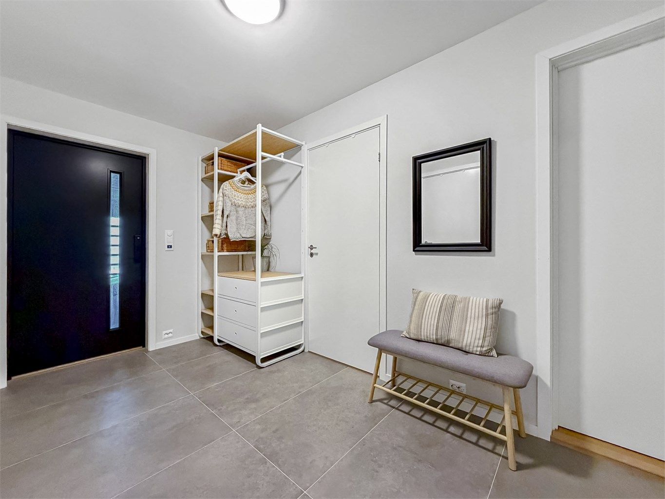 Romslig gang med lyse flater og store fliser på gulv med varmekabler.