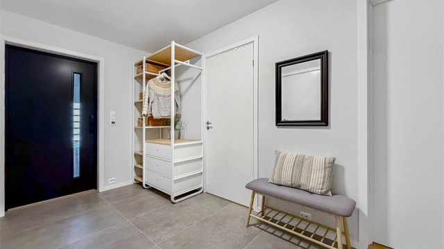 Romslig gang med lyse flater og store fliser på gulv med varmekabler.