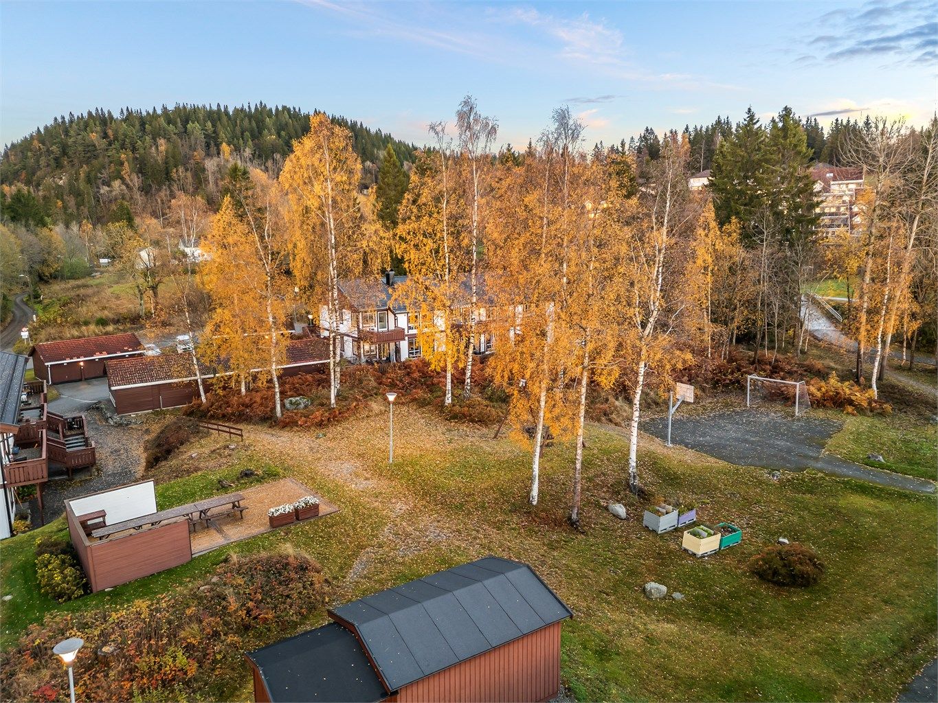 Pent opparbeidet fellesarealer med ballbane, huskestativ og platting med flere sittebenker samt levegger.